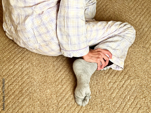 寝巻姿で足首をもむ高齢女性の手_後ろから Fotobehang