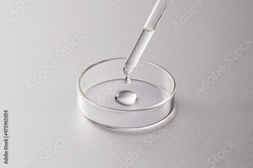 Petri dish with one dropper contained serum or acid or liquid on silver grey background photo