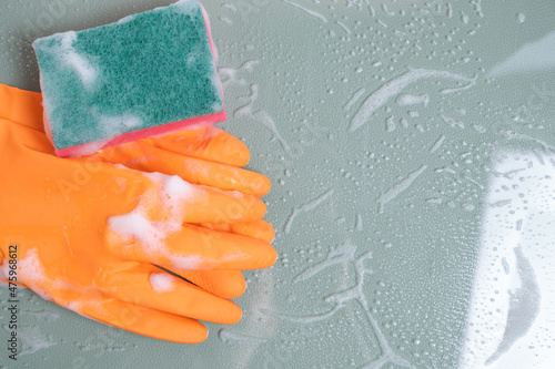 Gloves with a wet sponge for cleaning on glass covered with foam.