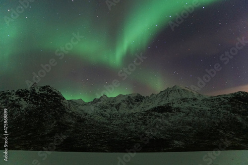 Beautiful Aurora Borealis over mountain and lake water in Kvaloya, Arctic region in Norway photo