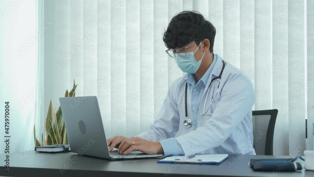 Asian doctor is working on a laptop computer and writes the patient's history in the office. Asian doctor is working on a laptop computer and writes the patient's history in the office.