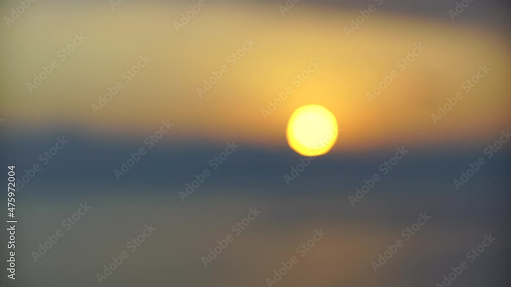 Sea surface small waves against golden slow motion sunrise. Large disk of the sun rises above the sea blurred background, sunny path on the water, clouds. Golden light of the sea panorama. Relax Sea surface small waves against golden slow motion sunrise. Large disk of the sun rises above the sea blurred background, sunny path on the water, clouds. Golden light of the sea panorama. Relax
