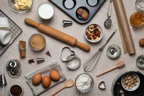 Baking background. Baking tools and food ingredients for baking - flour, eggs, sugar, milk, nuts on beige background. Baking or cooking cakes or muffins. Top view, flat lay.
