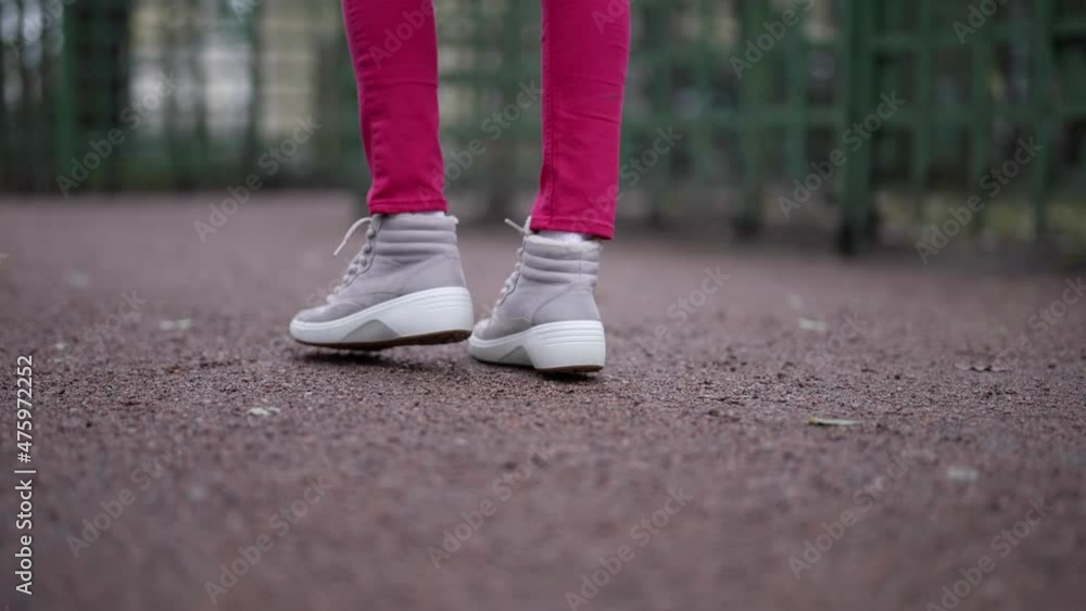 sporty street style in city, closeup of feet of young woman strolling on pedestrian path sporty street style in city, closeup of feet of young woman strolling on pedestrian path
