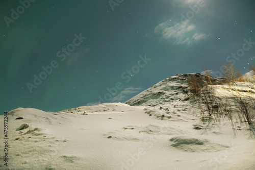 Breathtaking view of the Aurora Borealis over a snowy mountain in Kvaloya, Arctic region in Norway photo