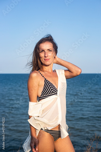 Beautiful sexy young woman on the background of the sea on a summer day.