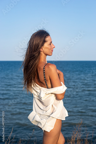 Fototapeta Naklejka Na Ścianę i Meble -  Beautiful sexy young woman in a light pareo on a cliff looks at the sea.