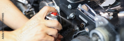 Foto Master repairman puffing grease on motorcycle part closeup