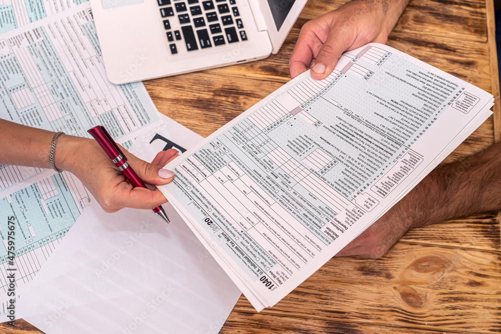 Naklejka premium two employees at work fill out tax forms 1040 at the office desk.