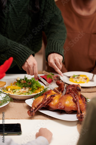Woman cutting grilled chicken at Christmas dinner table