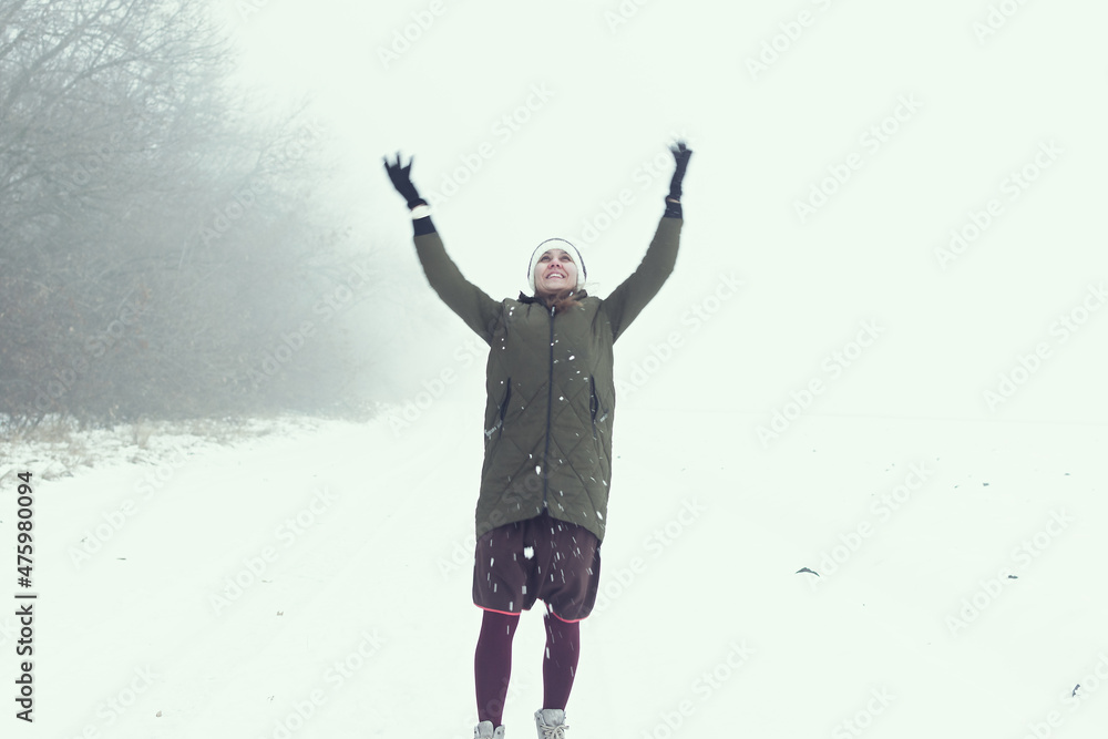 Young woman winter landscape. A beautiful brunette enjoys the first fluffy clean snow on a deserted road. A magical journey into childhood. The concept of winter mood, joy, fun, naivety of simplicity Young woman winter landscape. A beautiful brunette enjoys the first fluffy clean snow on a deserted road. A magical journey into childhood. The concept of winter mood, joy, fun, naivety of simplicity