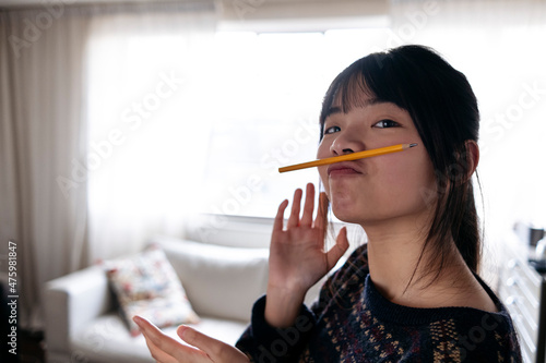 Young woman holding pencil on puckered lips at home