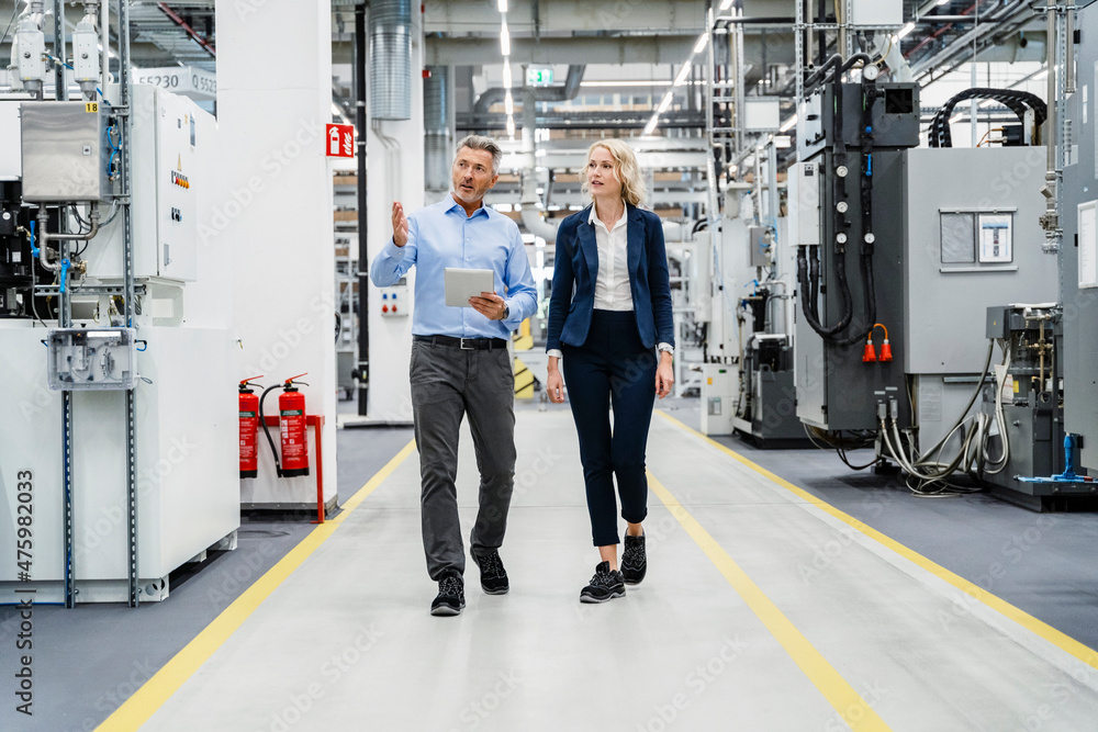 Businessman inspecting machinery with coworker in automated factory Businessman inspecting machinery with coworker in automated factory