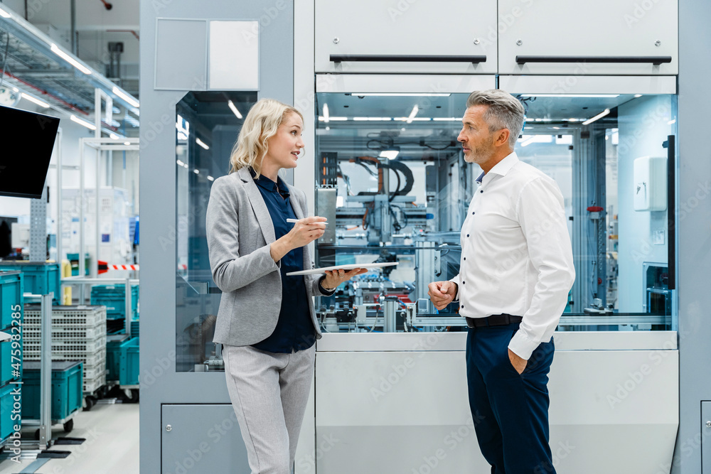 Businesswoman with tablet PC explaining to coworker in industry Businesswoman with tablet PC explaining to coworker in industry