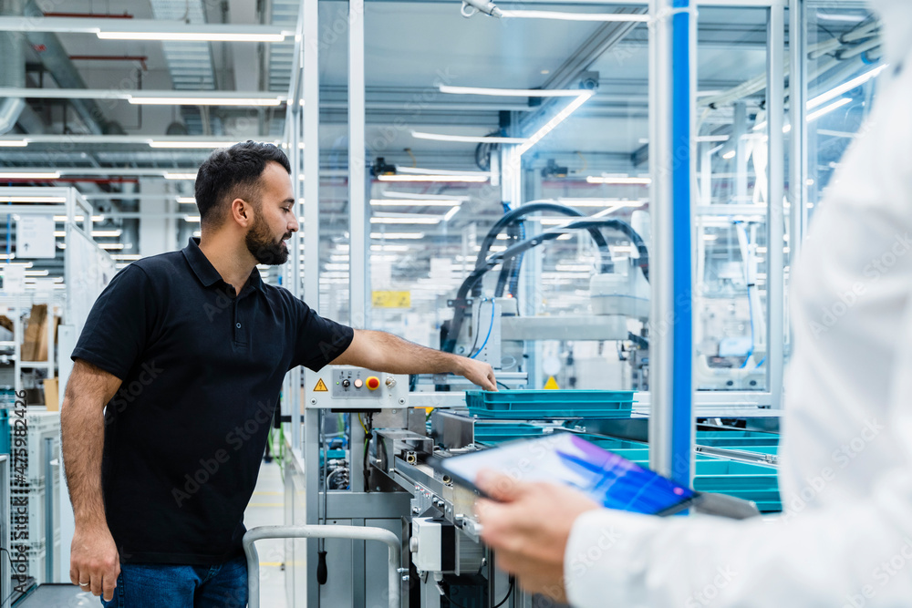 Businessman explaining maintenance engineer over factory production line Businessman explaining maintenance engineer over factory production line