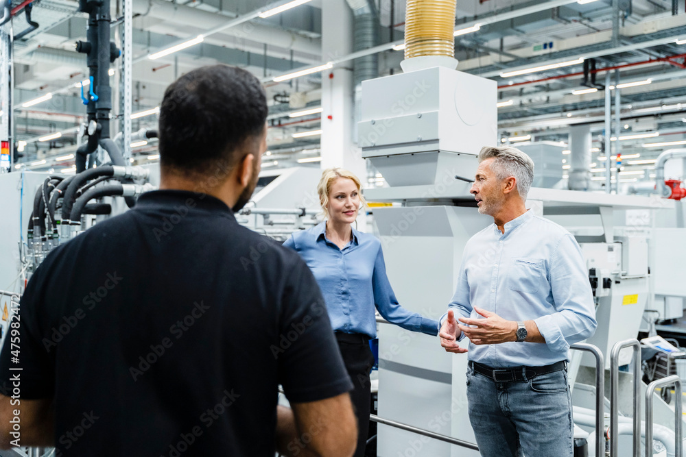 Businessman having discussion with colleagues at industrial machinery Businessman having discussion with colleagues at industrial machinery