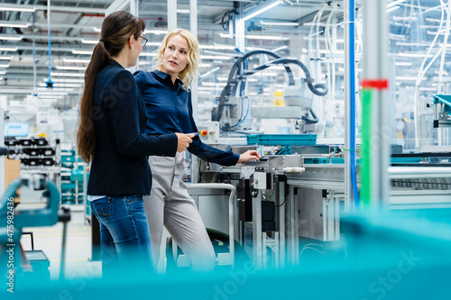 Businesswoman discussing with colleague at factory production line photo