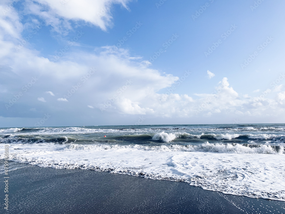 Seascape, white clouds on the blue sky reflection, sea surface, sand beach