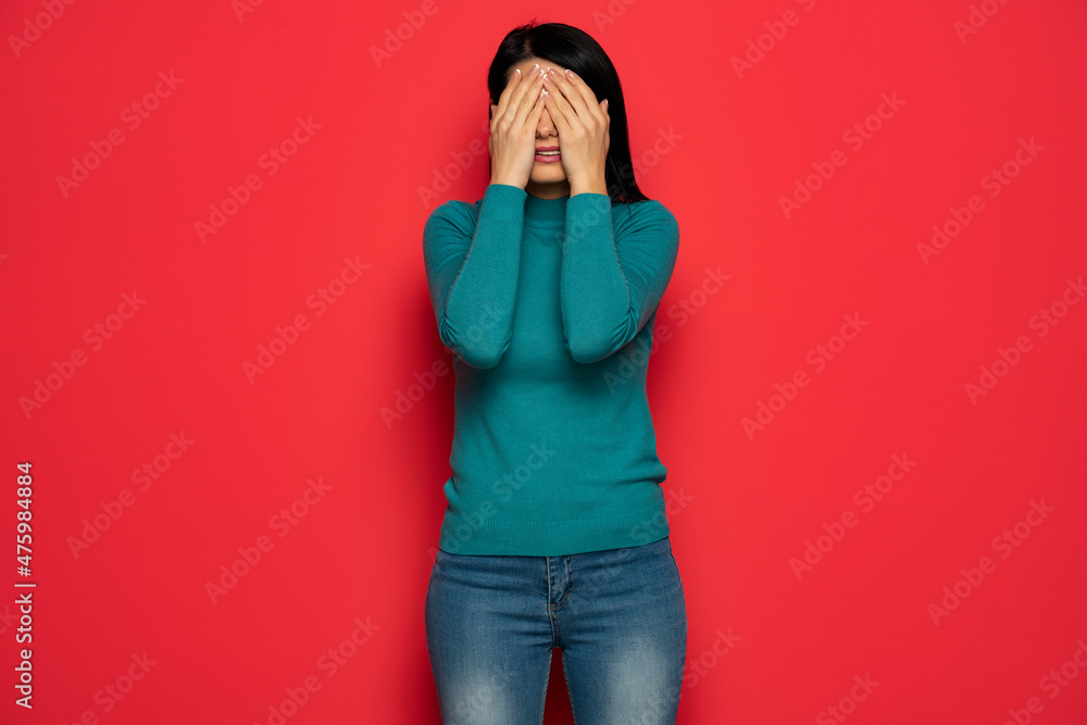 young woman covering her eyes with her hand palms on red background young woman covering her eyes with her hand palms on red background