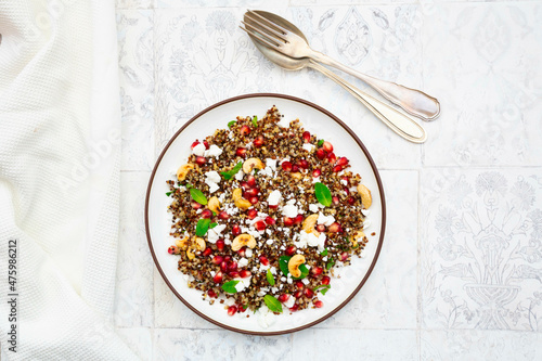 Studio shot of plate of quinoa salad with feta cheese, pomegranate seeds and cashews photo