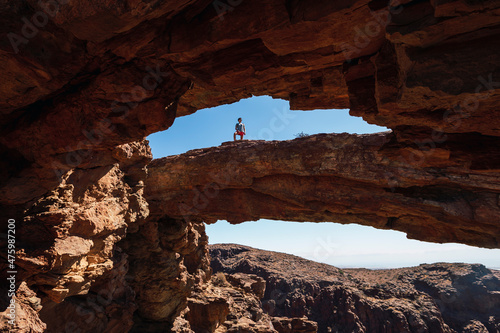 Man standing on natural rock arch in Gran Canaria, Spain photo