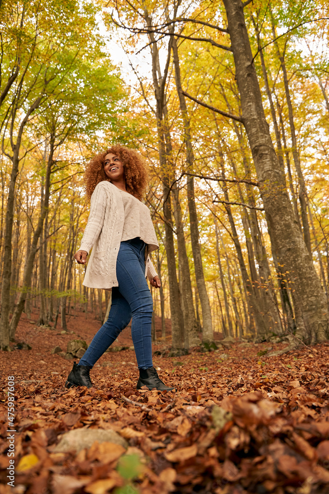 Smiling young woman walking on leaves in autumn forest Smiling young woman walking on leaves in autumn forest