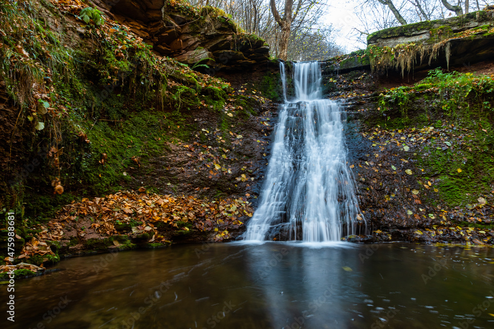 Obraz premium Tranquil waterfall scenery in the middle of autumn forest