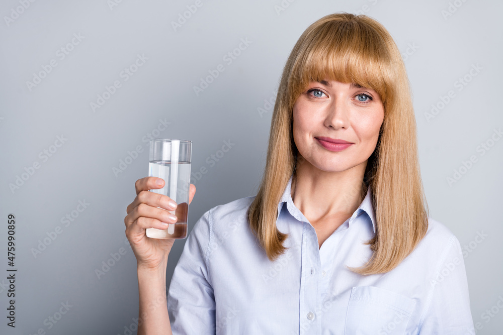 Photo of adorable woman wear formal shirt drinking clear water empty space isolated grey color background Photo of adorable woman wear formal shirt drinking clear water empty space isolated grey color background