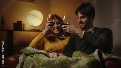 Coppia beve dai calici di vino sul divano in casa photo