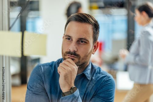 Thoughtful caucasian office worker, looking at the notes and thinking.