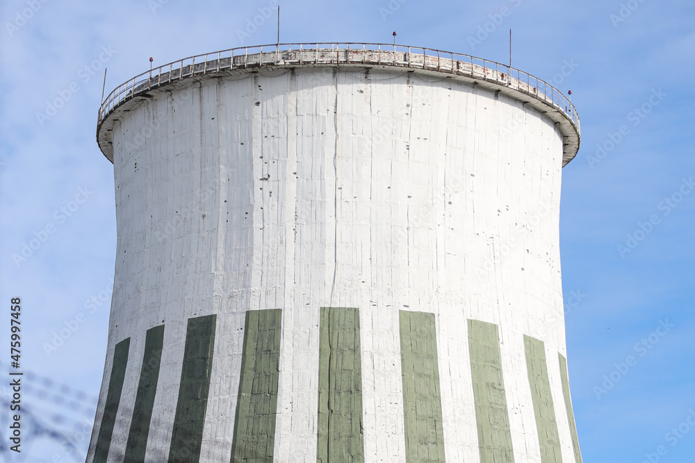 Large round white chimney industrial electric tower view building structure with barbed wire in foreground. Large round white chimney industrial electric tower view building structure with barbed wire in foreground.