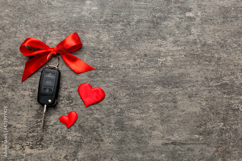 Car key with a red bow and a heart on Colored table. Giving present or gift for valentine day or christmas, Top view with copy space
