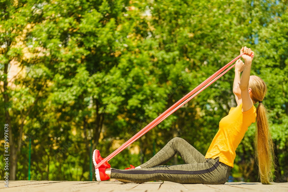 Girl doing exercise outdoor, using resistance fit band.