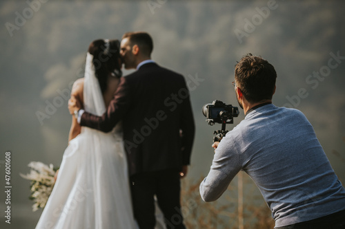 Foto Closeup shot of a photographer taking a photo of the bride and groom kissing eac
