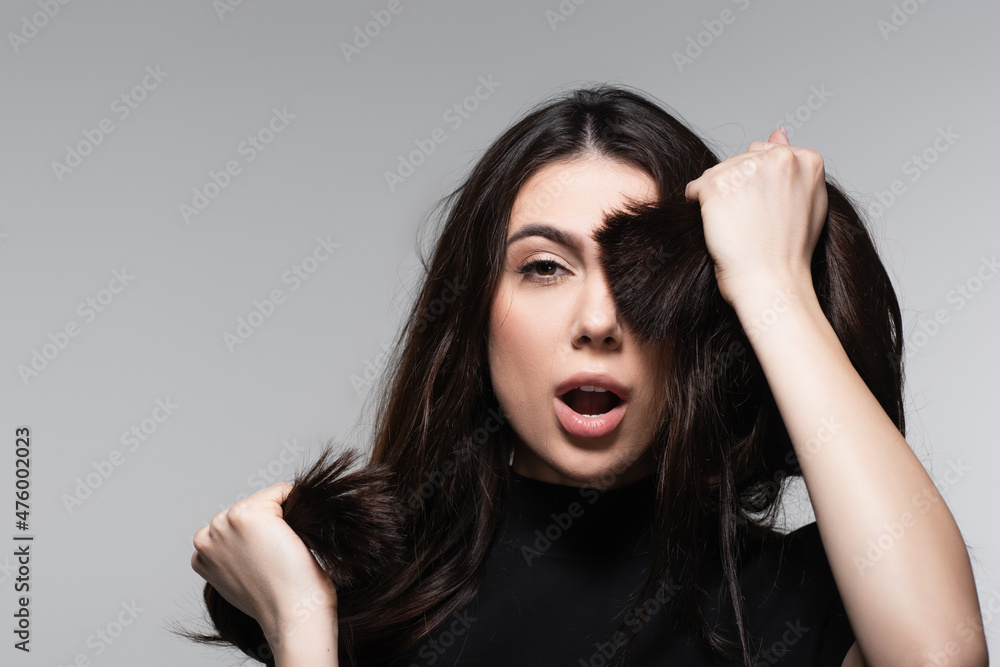 shocked young woman covering eye with brown hair isolated on grey shocked young woman covering eye with brown hair isolated on grey