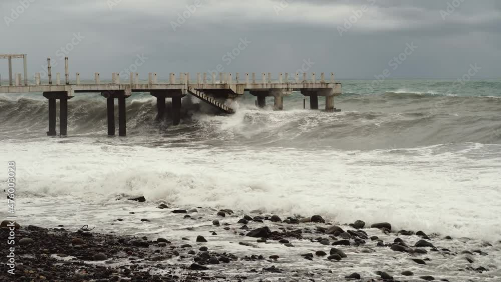 hurricane. Shots of pier with crashing waves. Sea foam, splashes of water, waves beating on shore. Storm at sea in resort town of Batumi in Georgia. Waves crash against a reinforced concrete pier. hurricane. Shots of pier with crashing waves. Sea foam, splashes of water, waves beating on shore. Storm at sea in resort town of Batumi in Georgia. Waves crash against a reinforced concrete pier.