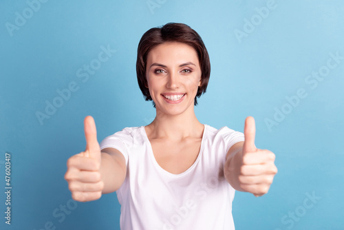 Photo of young cheerful girl show thumbs-up great advertising promotion isolated over blue color background © Tetiana