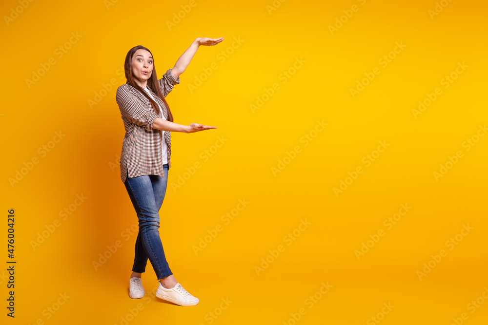 Full body profile side photo of young charming lady show hands measure size ads isolated over yellow color background Full body profile side photo of young charming lady show hands measure size ads isolated over yellow color background