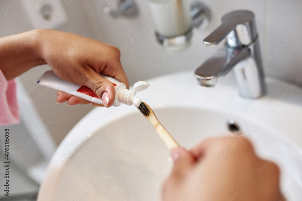 Hands of black woman put toothpaste on toothbrush