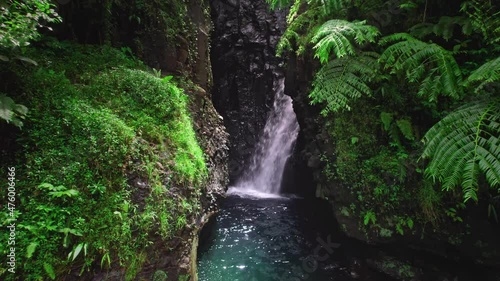 Aerial close up of beautiful waterfall in jungle. Drone flying through the tropical cascade cave. Nature of French Polynesia in Tahiti island.