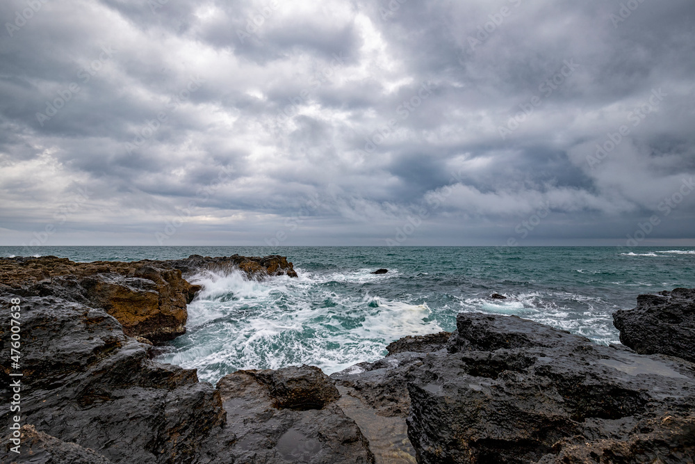 Stunning seascape with scenic clouds over the sea with rocky shore