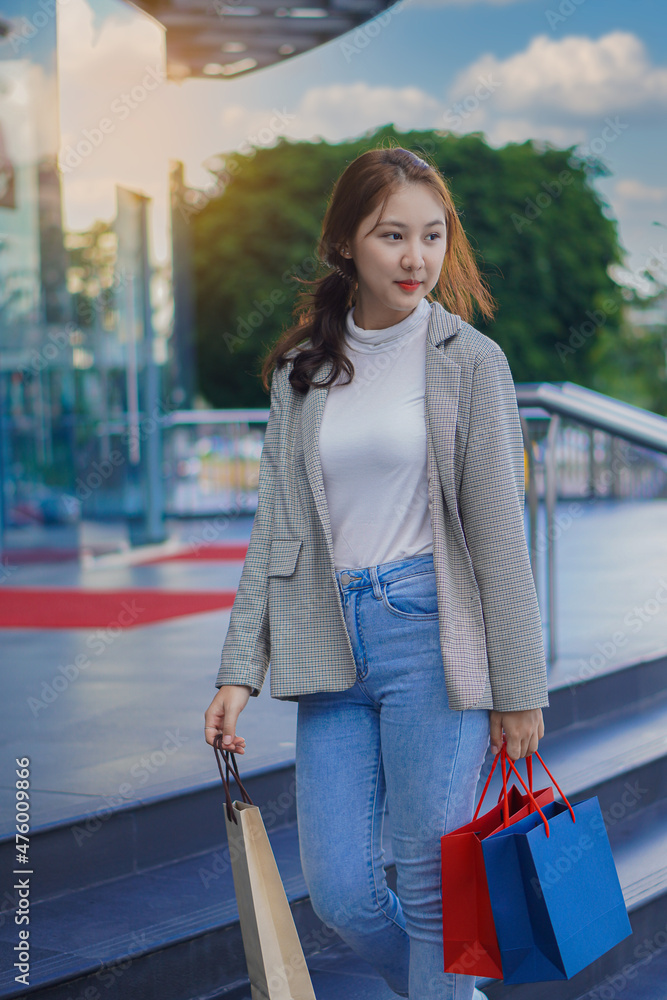 a beautiful girl standing in front of a boutique holding a shopping paper bag Portrait of a graceful young woman who enjoys shopping while shopping in the department store in the Sale season Copy spac