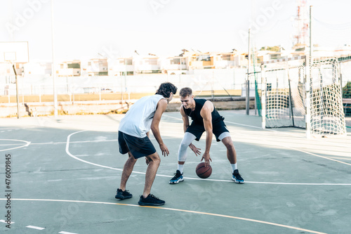 Man dribbling a friend while playing basketball outdoors