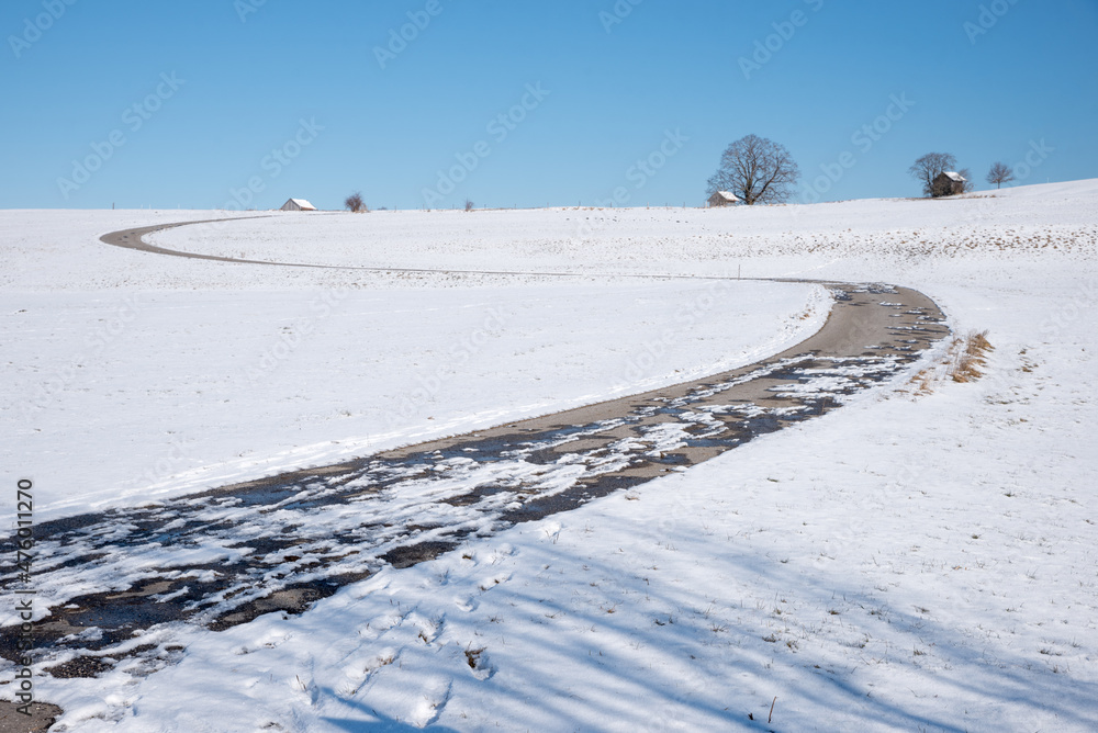 curvy road in snowy winter landscape, blue sky curvy road in snowy winter landscape, blue sky