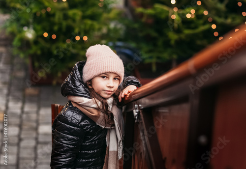 holidays, childhood and people concept - happy little girl at christmas market in winter evening photo