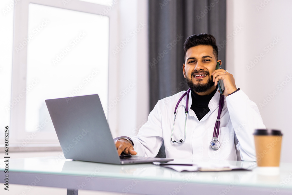 Young doctor phoning a patient in office Young doctor phoning a patient in office