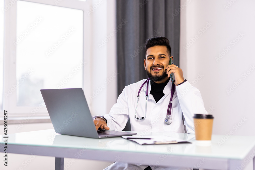 Medicine, healthcare and people concept. Young male doctor with clipboard calling on phone at clinic Medicine, healthcare and people concept. Young male doctor with clipboard calling on phone at clinic