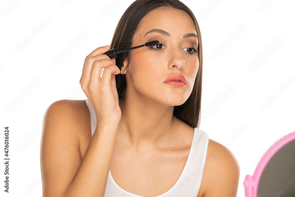a young woman applied mascara to her lashes on white background a young woman applied mascara to her lashes on white background