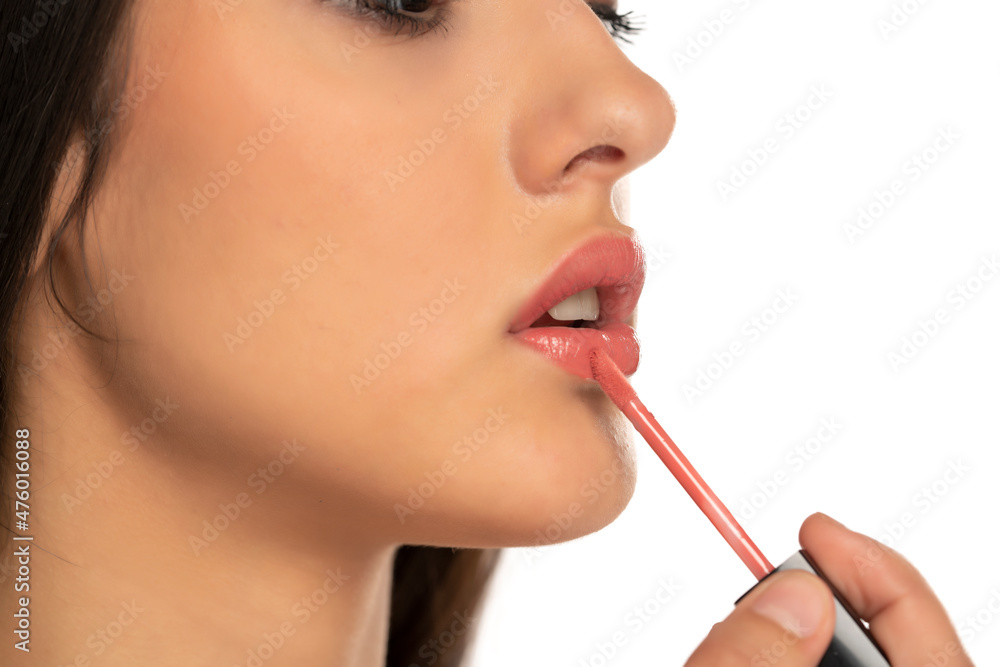 Closeup of woman applying a lip gloss on her lips