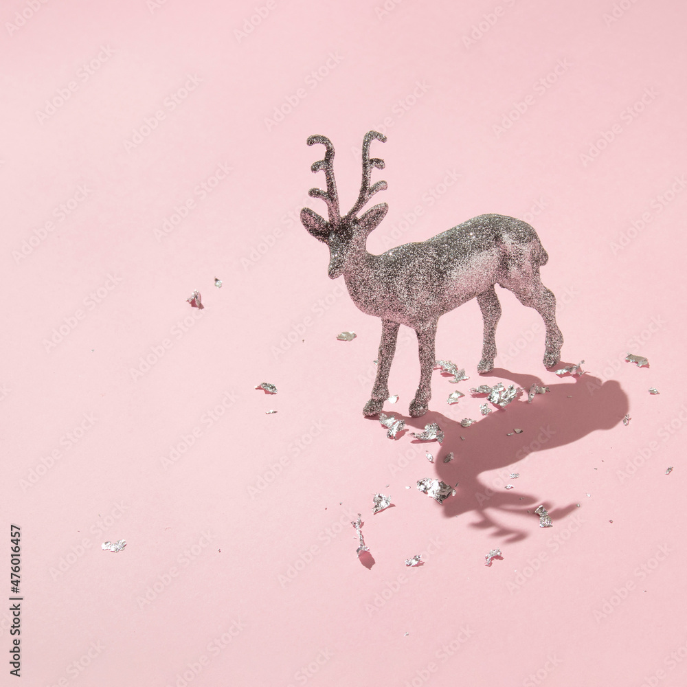 Creative layout with glitter reindeer decoration and silver foil leaf flakes on pastel pink background. New Year celebration creative idea. 80s or 90s retro aesthetic christmas minimal concept. Creative layout with glitter reindeer decoration and silver foil leaf flakes on pastel pink background. New Year celebration creative idea. 80s or 90s retro aesthetic christmas minimal concept.